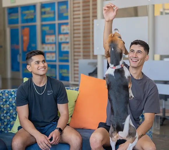 two young men playing with a dog